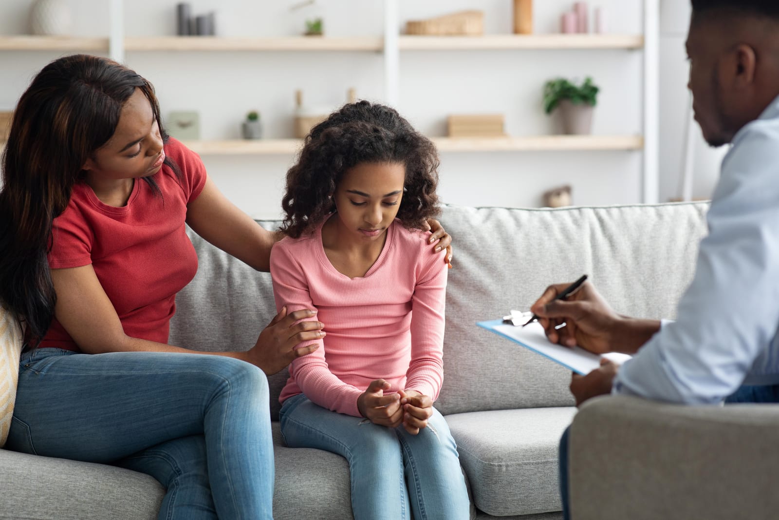 A behaviour support specialist meeting with a mother and her daughter on a sofa