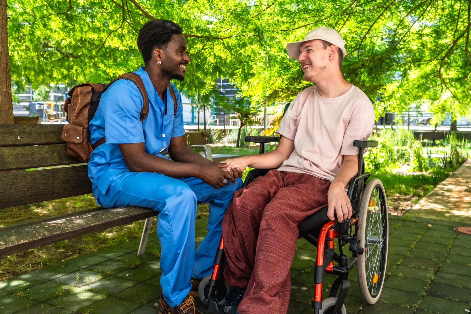 A Zinovative care worker sharing a warm conversation with a young man using a wheelchair outdoors