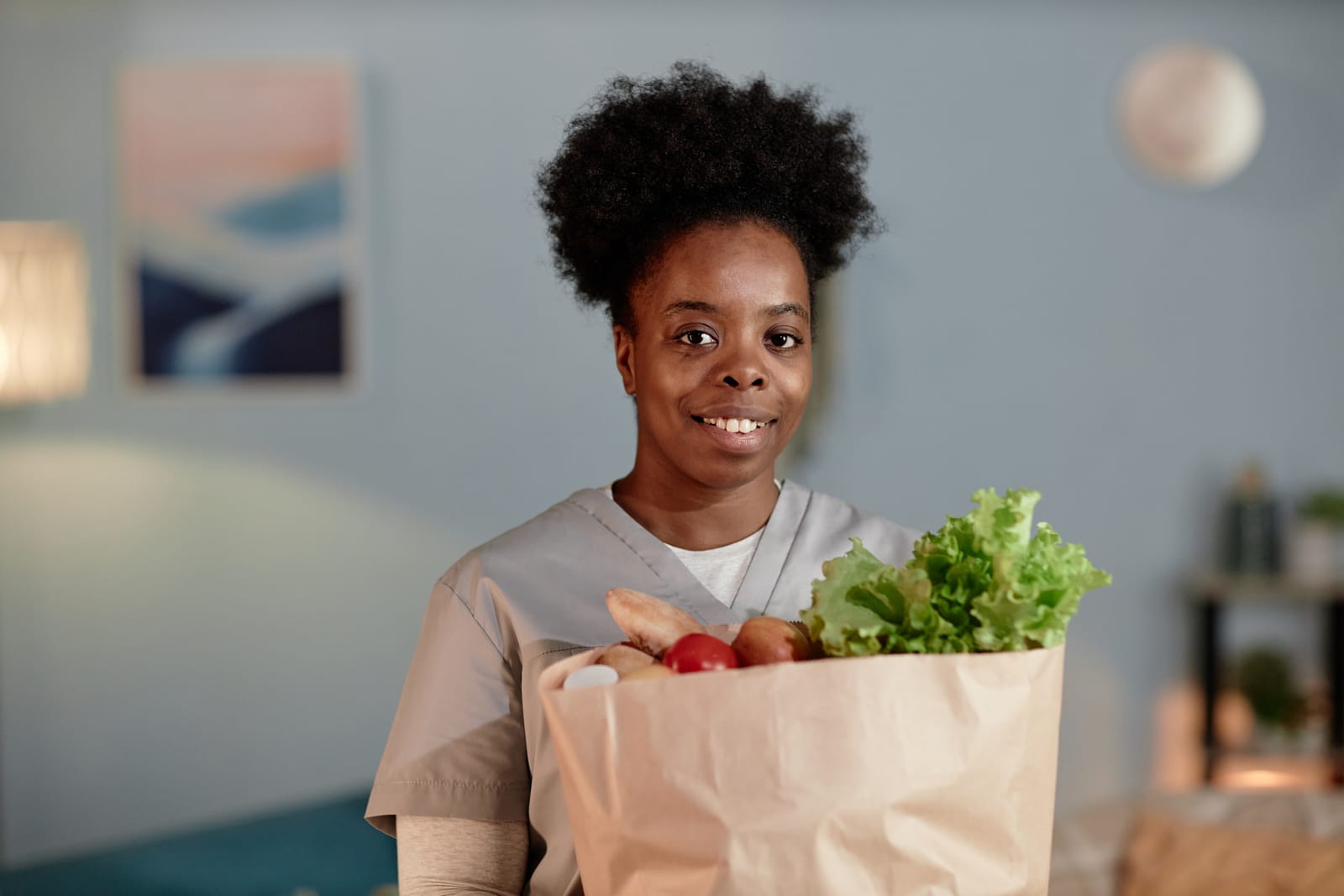 A smiling home support worker carrying fresh groceries, ready to help with everyday life